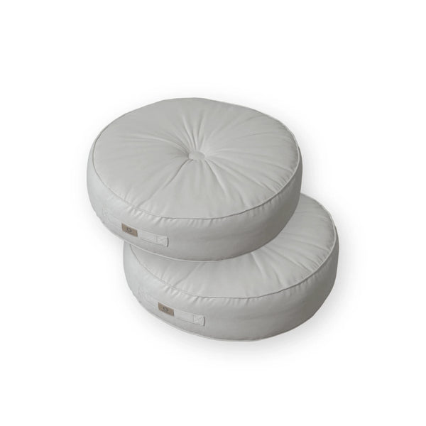 Deux poufs ronds en velours gris clair avec poignée, design doux, parfaits pour la décoration intérieure.