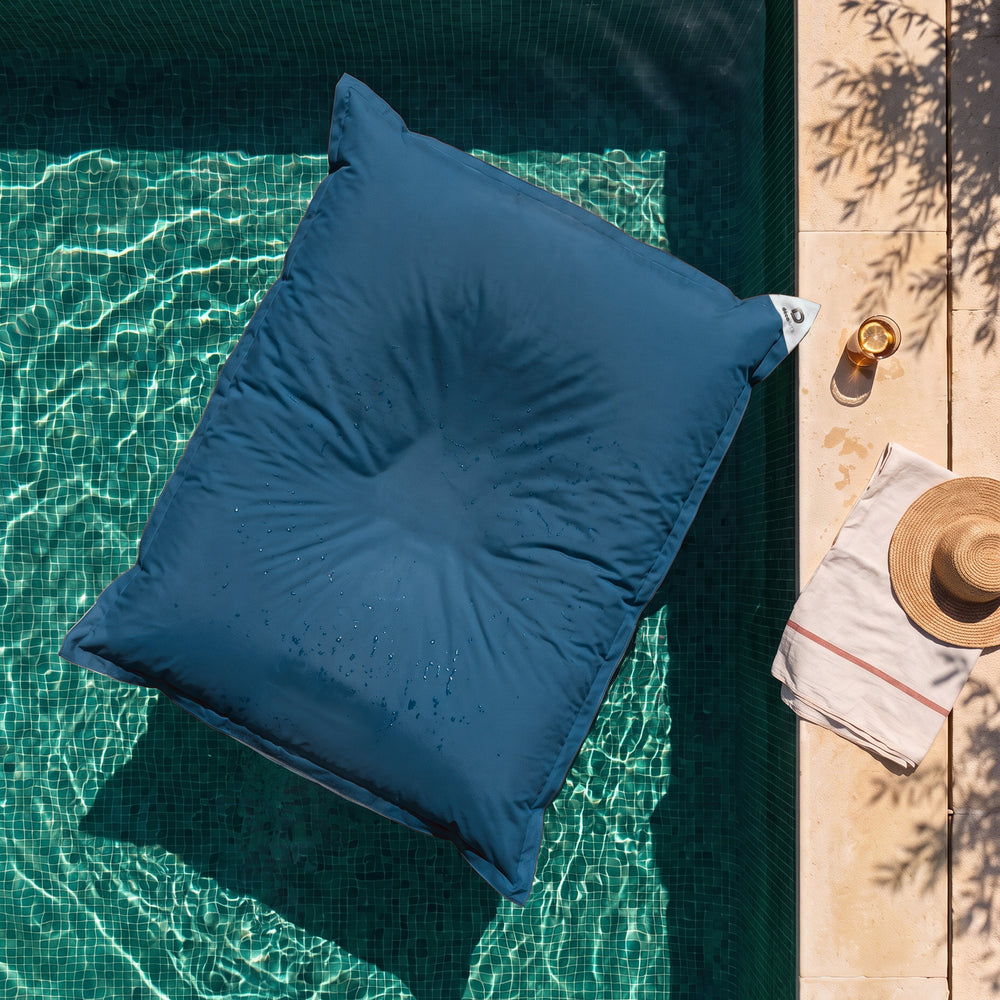 Pouf géant flottant Bleu Pétrole sur l'eau d'une piscine, vue du dessus