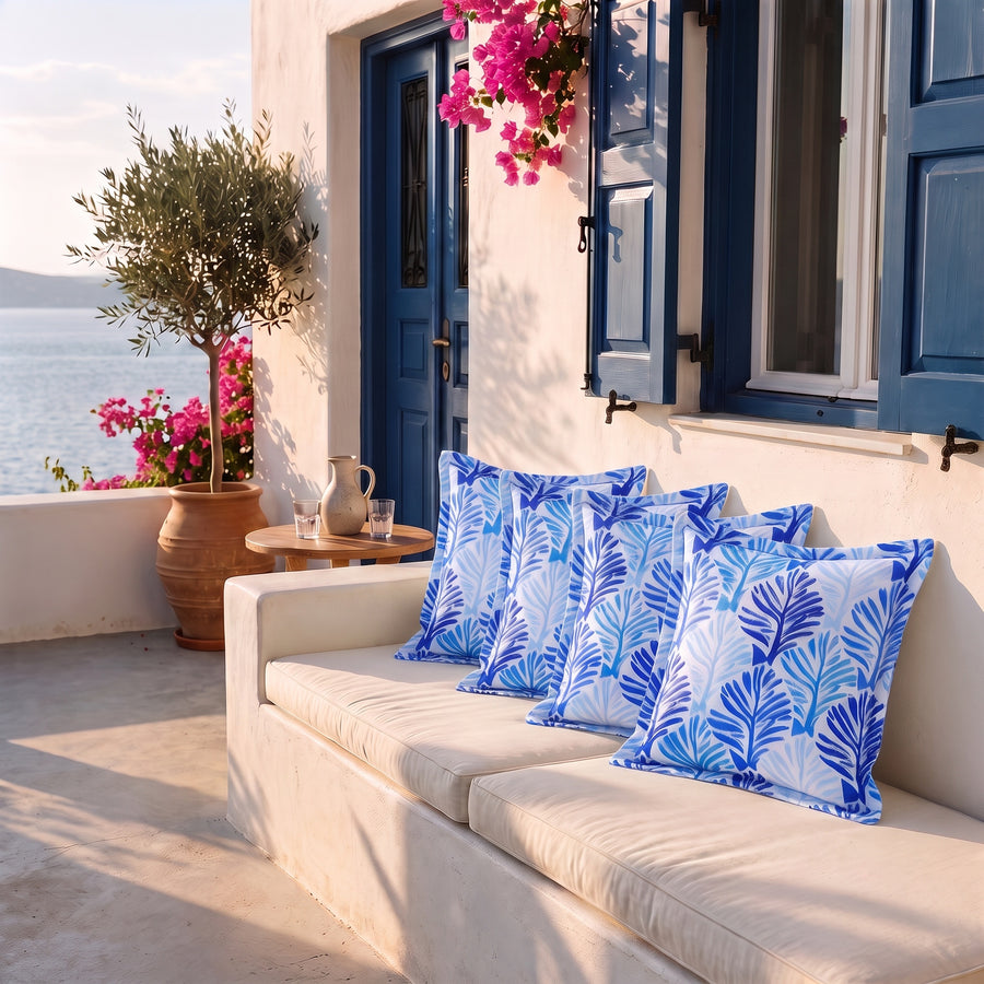 Lot de 4 coussins déco 45x45 motif Feuillage Bleu sur une banquette de terrasse face à la mer