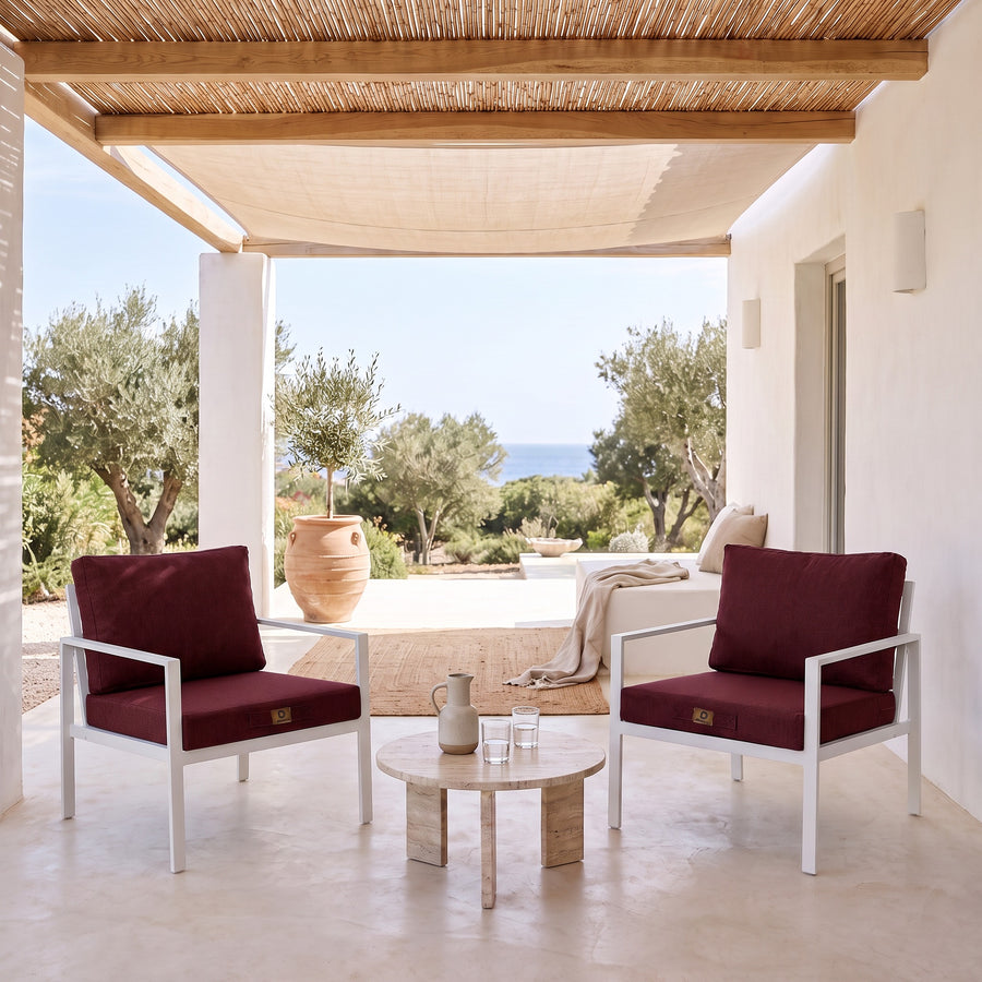 Fauteuilkussens met linnenlook in Pruim op twee witte fauteuils onder een overdekte pergola, licht terras uit de zon