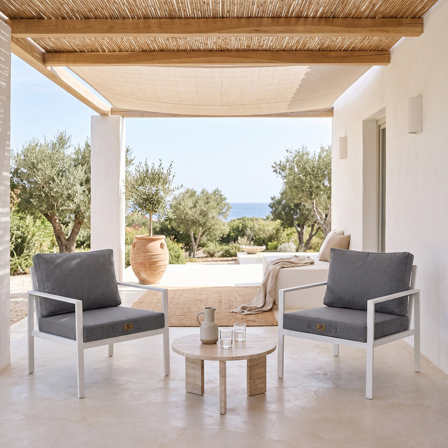 Fauteuilkussens met linnenlook in Gemêleerd Grijs op twee witte fauteuils onder een overdekte pergola, licht terras uit de zon