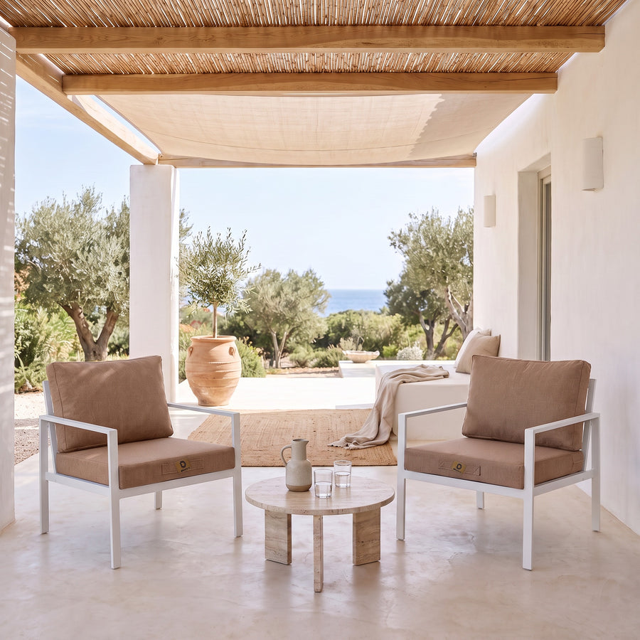 Fauteuilkussens met linnenlook in Terracotta op twee witte fauteuils onder een overdekte pergola, licht terras uit de zon