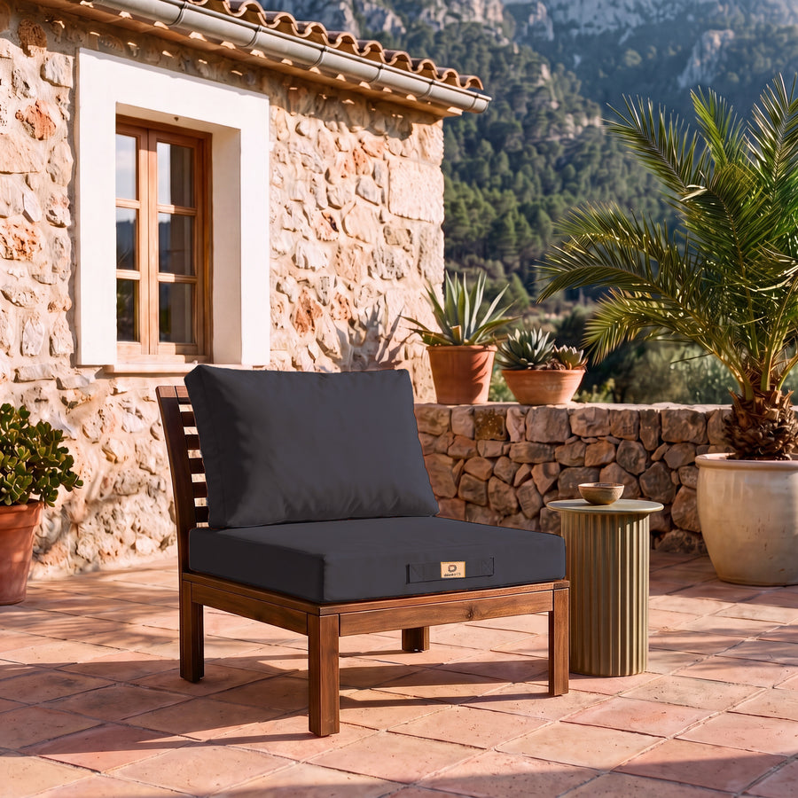 Tuinlounge kussenset 50x60 in Koolstofgrijs op een houten fauteuil, terras van een Mallorcaanse finca