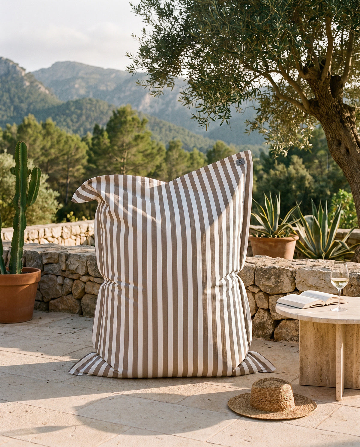 Pouf géant rayé beige Deco Arts sur une terrasse de finca à Majorque, olivier et montagnes