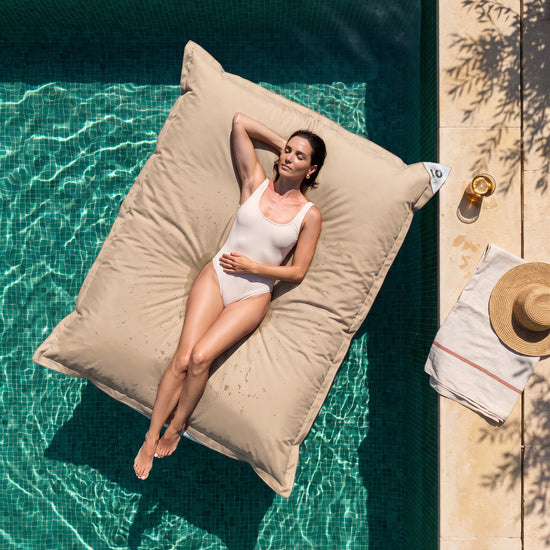 Nur Bezug, zum Befüllen – Riesen-Schwimmsitzsack 180 × 140 cm in Beige auf einem Pool, Frau in der Sonne, Draufsicht