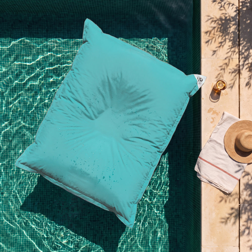 Alleen hoes, zelf te vullen – Reuzen drijvende zitzak in Caribisch Blauw op het water van een zwembad, bovenaanzicht