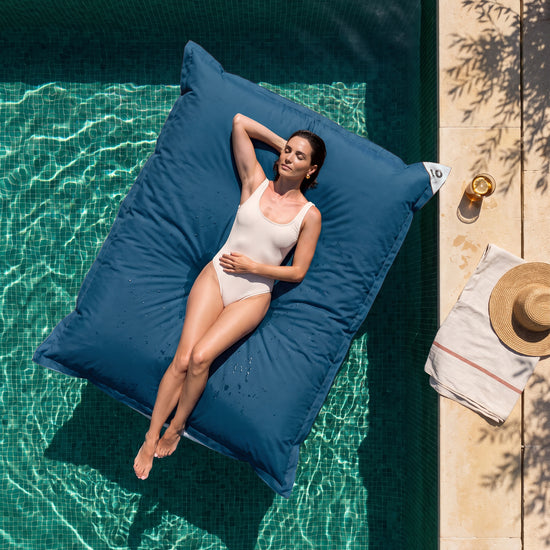 Nur Bezug, zum Befüllen – Riesen-Schwimmsitzsack 180 × 140 cm in Petrolblau auf einem Pool, Frau in der Sonne, Draufsicht